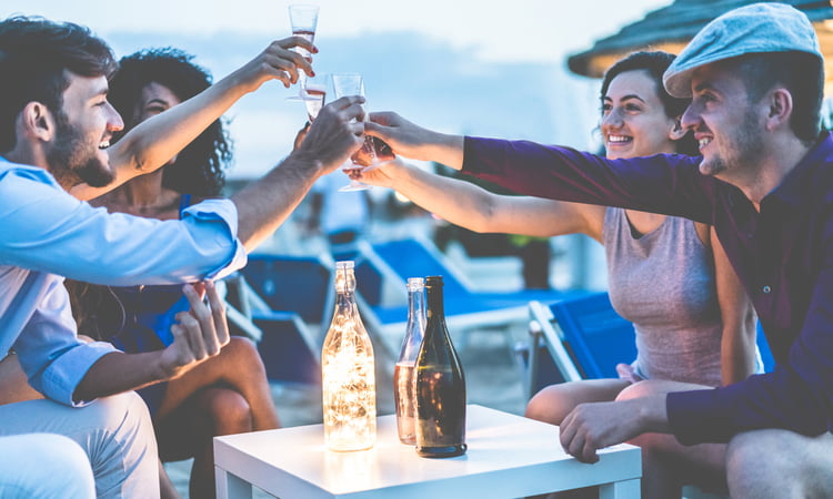 group of young people drinking at sunset on the beach