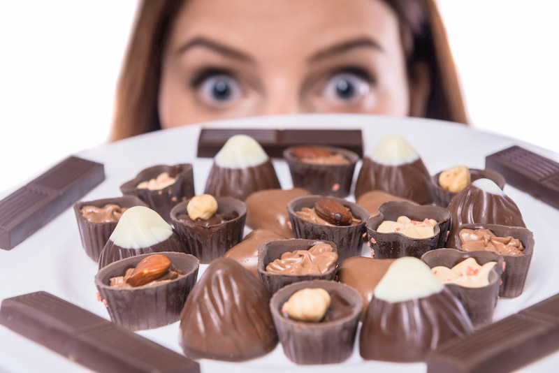 a woman holds a plate of small chocolates