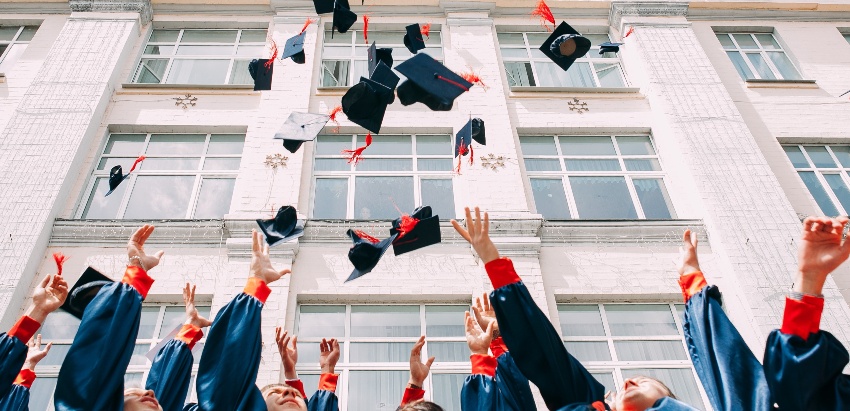 college graduates tossing their graduation caps