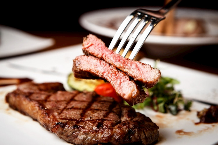 Person using a fork to dig into a steak