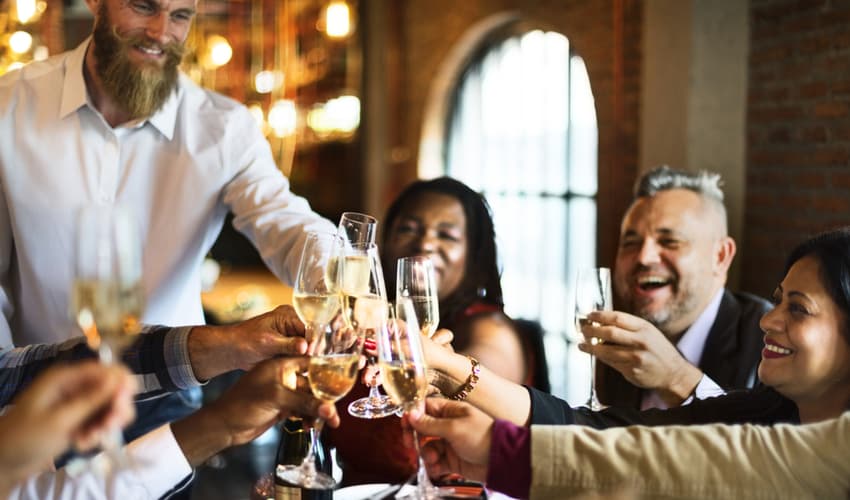 people toasting white wine at a dining table