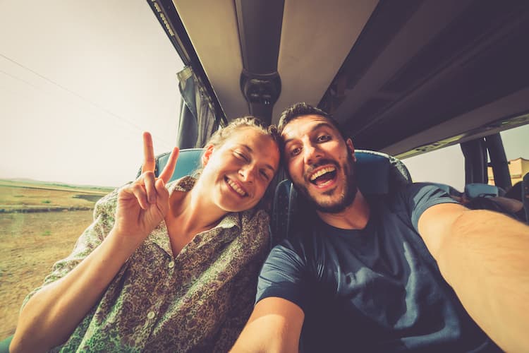 Young man and woman taking a selfie together on a charter bus trip.