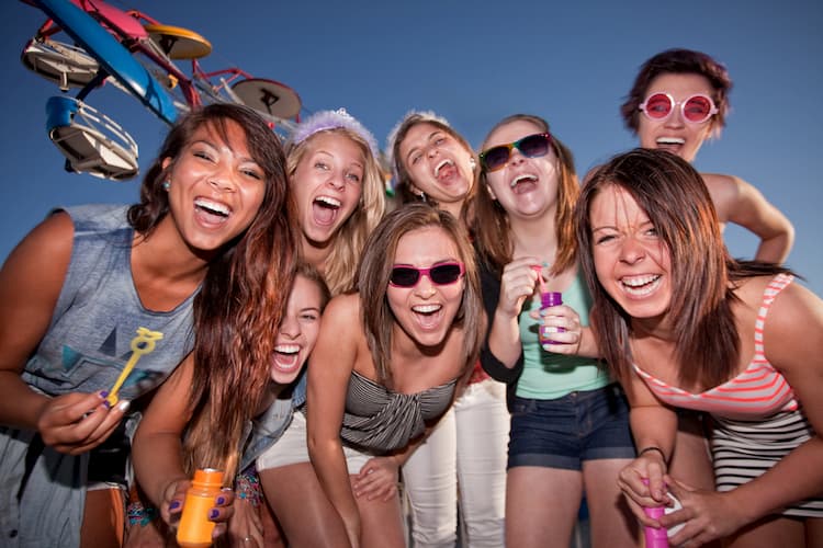 Group of happy women blowing bubbles and laughing at an amusement park.