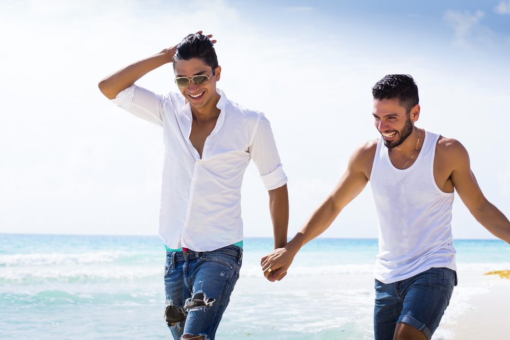 Two men holding hands on the beach