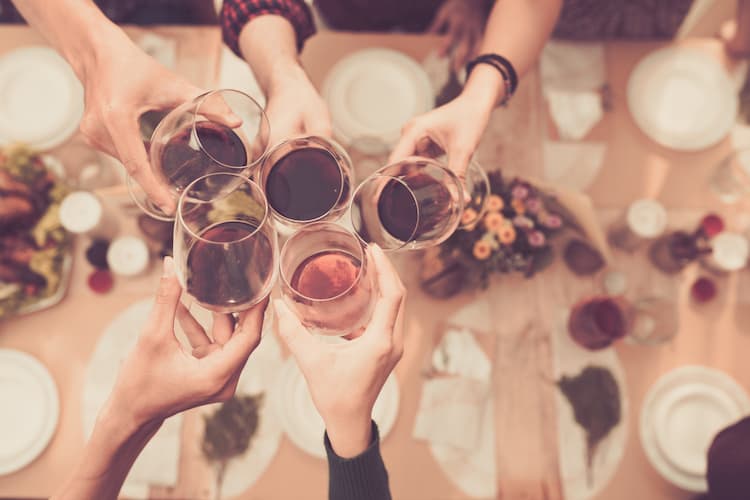 friends toast their wine glasses over an upscale table setting