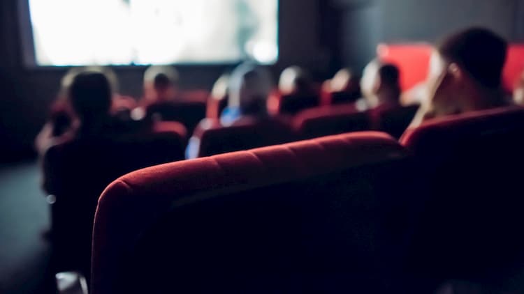 theatre seats in a dark theater with a movie playing on the screen