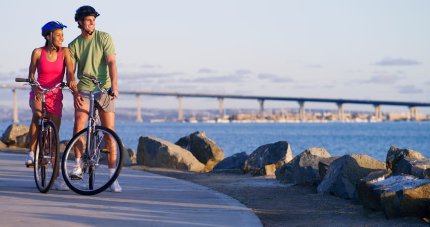 A happy couple bikes along a waterfront sidewalk