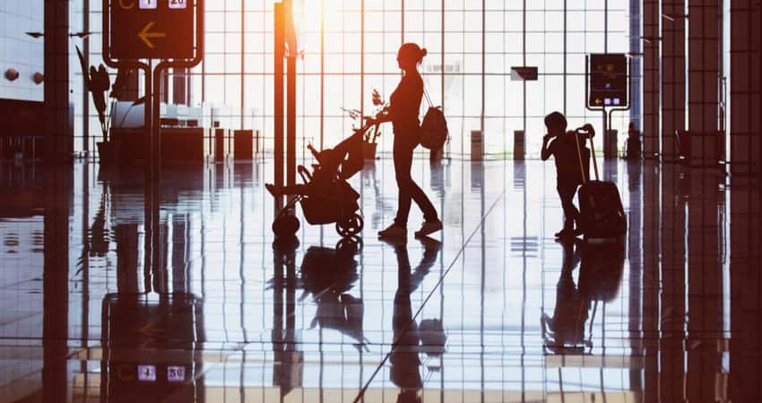 A family walking in an airport against a strongly backlit window