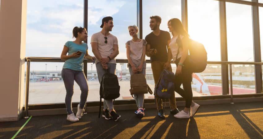 A group of people chatting in front of a backlit window in an airport.