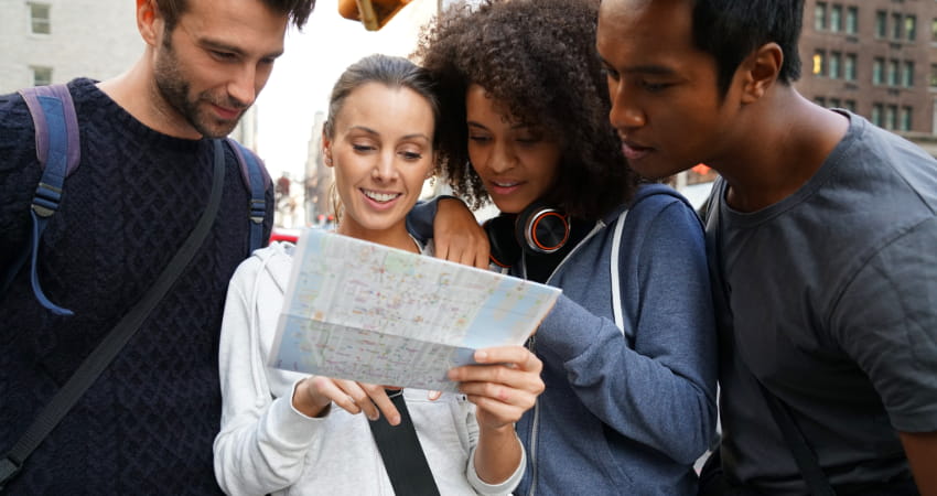 A group of tourists check a map in a city sidewalk