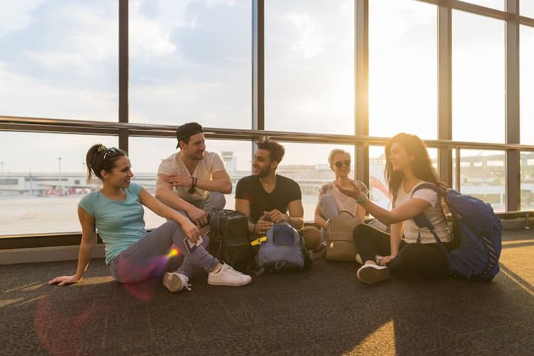 Five friends sitting on floor of airport
