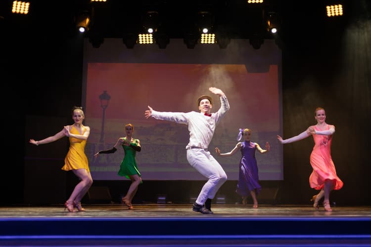 Four women and one man dancing in a musical