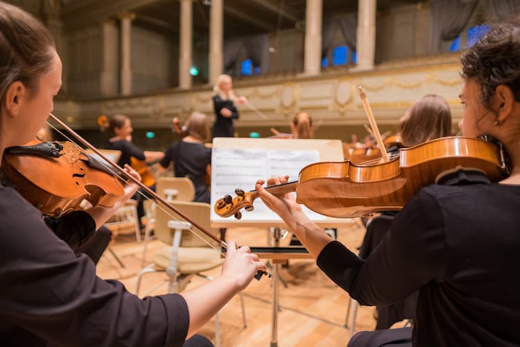 Two women playing violin in symphony orchestra