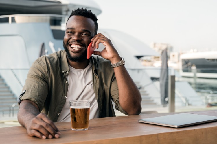 a man calls friends on his phone while he waits at a brewery