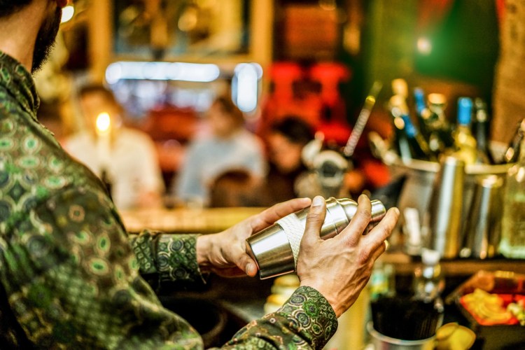 a bartender mixes a drink with a shaker