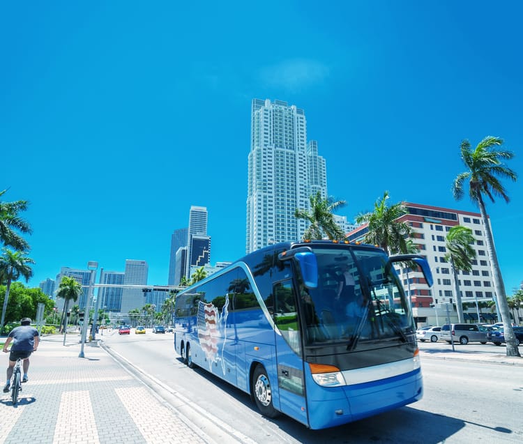 a blue charter bus parked on the side of a miami street