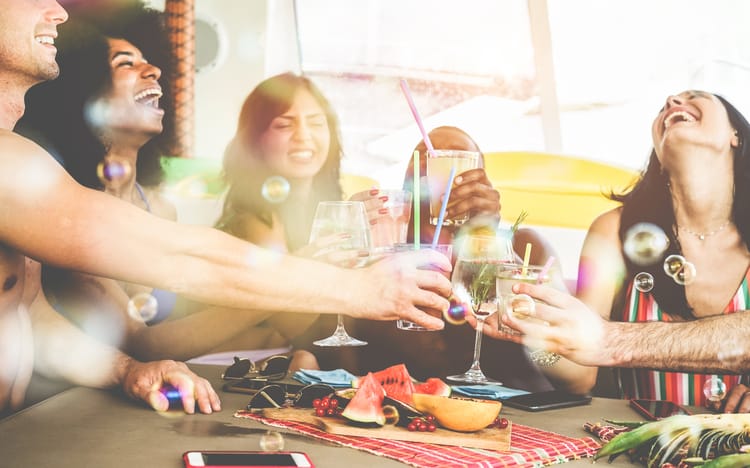 friends cheers their glasses and smile around a table filled with food