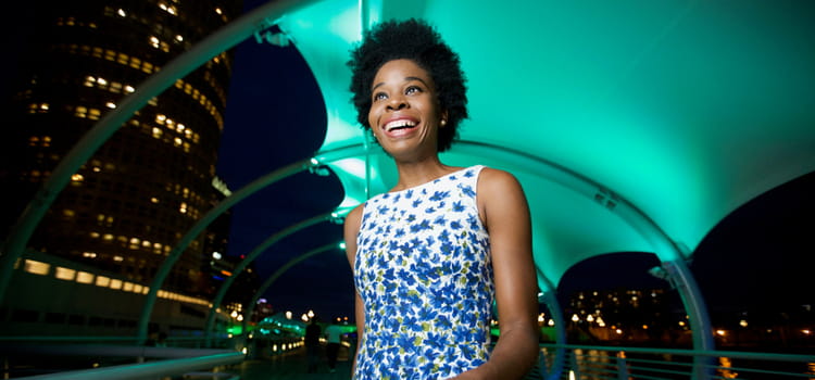 a woman smiles while walking through an illuminated tunnel after dark