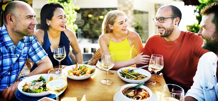 friends gather around a table outside to eat and drink