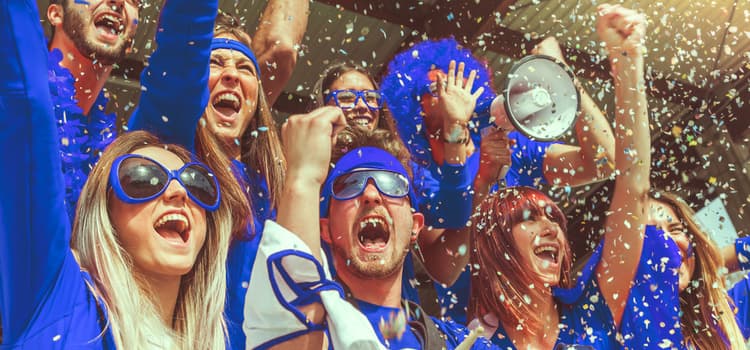 sports fans wearing blue celebrate and cheer while blue confetti falls