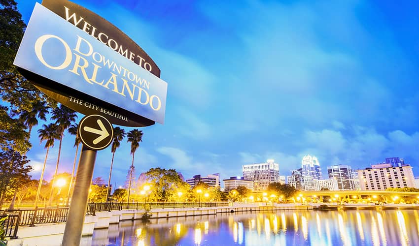 a sign reads 'welcome to Orlando' with the city skyline in the background