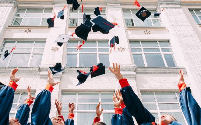 college graduates tossing their graduation caps