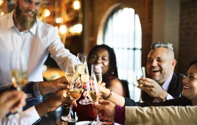 people toasting white wine at a dining table