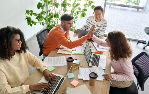 a team high-five while discussing a business plan