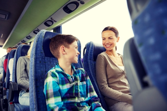 a child and his mother smile at each other on a charter bus